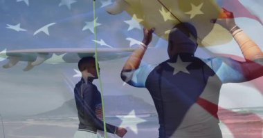 Üzerinde Amerikan bayrağı olan sörf tahtaları, kumsalda yürüyen sörfçüler. Vatanseverlik, okyanus, sörf, kıyı, yaz, yaşam tarzı