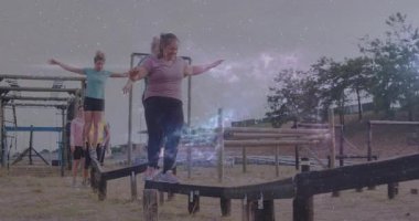 Açık hava engelli parkurunda parlayan ışık animasyon efektiyle dengelenen insanlar. Macera, takım çalışması, meydan okuma, açık hava, aydınlanma, aktivite