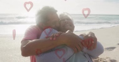 Sahilde kucaklaşan, arka planda kalp animasyonu olan yaşlı çift. Romantizm, aşk, sevgi, ilişkiler