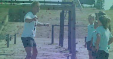 Açık hava eğitim sahasında koç, genç sporcuları coşkuyla karşılıyor. Spor, koçluk, takım çalışması, motivasyon, rekabet, egzersiz