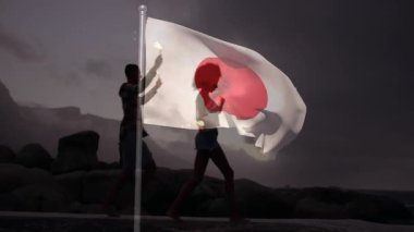 Japon bayrağını sallayarak kayalık arazide yürüyen insanların siluetinin üzerinde yürüyordu. Vatanseverlik, özgürlük, kültür