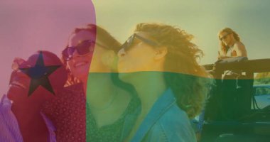 Gün batımını izliyoruz, Gine-Bissau bayrak animasyonu ile kumsalda dostlar. Seyahat, arkadaşlık, eğlence, okyanus, kutlama, kaçamak