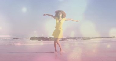 Kumlu sahilde neşeyle dönen, sarı elbiseli kadın animasyon yaratıyor. Tatil, özgürlük, yaratıcılık, yaz, yaşam tarzı, mutluluk