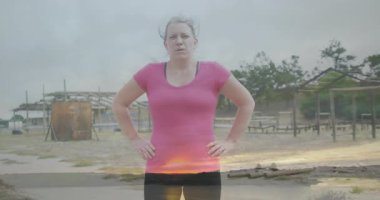 Kendine güvenen bir kadın, gün batımı manzaralı açık hava eğitim alanında duruyor. Zindelik, güven, egzersiz, kararlılık