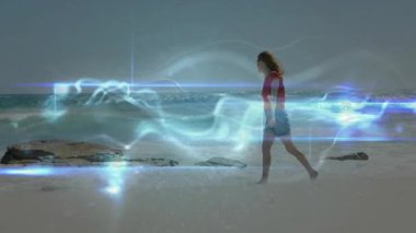 Kumsalda yürüyen bir kadın soyut ışık animasyonuyla çevrelenmiş. Günbatımı, siluet, sihir, gerçeküstü, fantezi, huzur