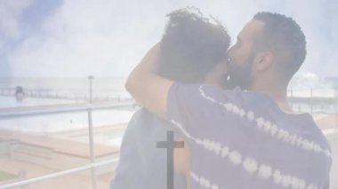 Çapraz sembol ve animasyon örtüsüyle sahil kenarında kucaklaşan çift. Romantizm, manevi, aşk, ilişki, sahil, sükunet