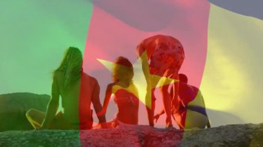 Kayaların üzerinde oturan, kamerun bayrağı taşıyan insanlar, açık havada güneşli bir günün tadını çıkarıyorlar. Ulusal bayrak, eğlence, vatanseverlik, topluluk, kutlama, manzara