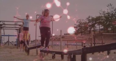 Açık hava engelli parkurunda parlayan ışık animasyonu ile dengelenen insanlar. Macera, takım çalışması, meydan okuma, denge, koordinasyon, açık hava