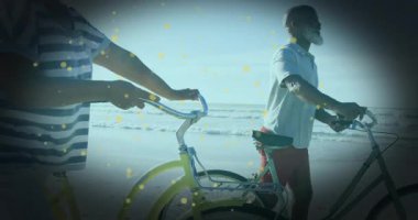 Sahilde parlayan parçacık animasyonlarıyla bisiklet süren yaşlı bir çift. Yaşlılar, tatil, dinlenme, deniz kenarı, dinlenme, bisiklet