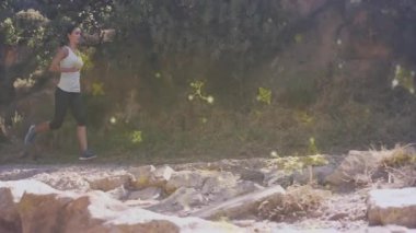 İz üstünde koşan kadın, animasyon gibi ışıldayan sarı parçacıklarla çevrili. Koşu, egzersiz, fitness, sihirli, ruhani, enerji