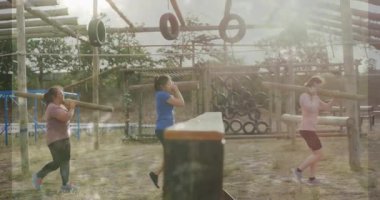 Açık hava engelli parkurunda egzersiz yapan, tahtadan ve lastik yapılarından geçen iki kadın. Fitness, antrenman, takım çalışması, macera, mücadele, spor