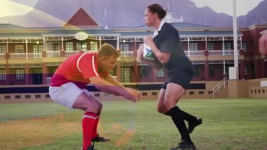 Sahada mücadele, arka planda okul binası olan ragbi oyuncuları görülüyor. Spor, takım çalışması, yarışma, sporcular, lise