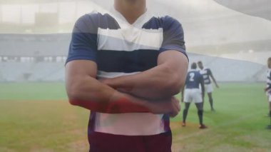 Sahada kendinden emin bir şekilde duran rugby oyuncusu, arka plan animasyonunda takım arkadaşlarıyla birlikte. Spor, takım çalışması, rekabetçi, sporcu, kararlılık, eğitim