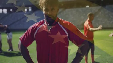 Kırmızı formalı ragbi oyuncusu Amerikan bayrağı animasyonuyla güvenle ayakta duruyor. Spor, atlet, vatanseverlik, şampiyonluk, güç, rekabet