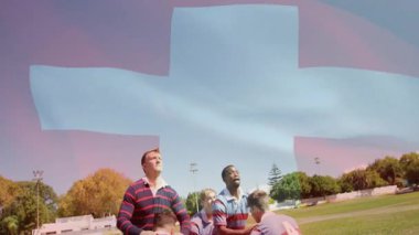 Rugby oyuncuları arka planda mavi haç animasyonuyla topu yakalamak için zıplıyorlar. Spor, takım çalışması, sporcular, yarışma, atlama, açık hava