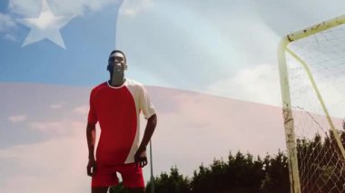 Kaleye doğru giden futbol topu, arka planda bayrak animasyonu olan oyuncu. Spor, futbol, atlet, yarışma, aksiyon, takım çalışması