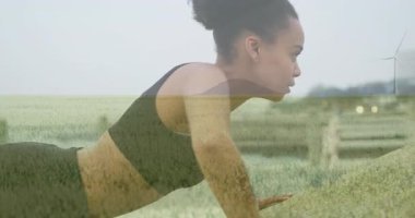 Egzersiz yapan kadın yeşil alan manzarasında rüzgar türbininin animasyonuyla örtülmüş. Sürdürülebilirlik, uygunluk, yenilenebilirlik, enerji, aerobik, çevre