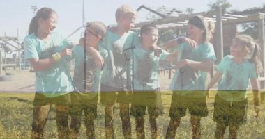 Tarlada, çamurlu giysiler içinde rüzgar türbinlerinin yanında gülümseyen çocuklar, animasyonun tadını çıkarıyorlar. Yenilenebilir, enerji, sürdürülebilir, çocukluk, açık hava, çevre