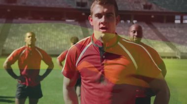 Kırmızı formalı ragbi oyuncuları bayrak kaplama animasyonlarıyla sahada duruyorlar. Spor, takım çalışması, yarışma, sporcular, stadyum, üniforma