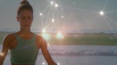 Sahilde meditasyon yapan, canlı yayın ağı bağlantıları olan bir kadın. Meditasyon, rahatlama, teknoloji, dijital, sağlık, sükunet