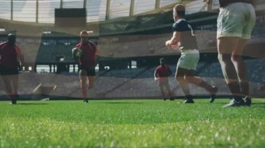 Ragbide mücadele eden oyuncular, büyük stadyumdaki yeşil sahada yarışıyorlar. Spor, rekabet, takım çalışması, sporcular, aksiyon