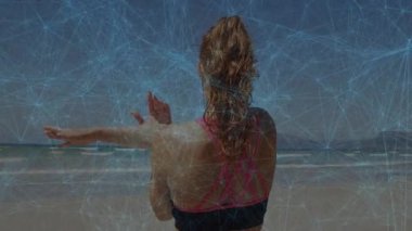 Sahilde spor giyimli bir kadın dijital ağ ile animasyonu örtüyor. Fitness, teknoloji, egzersiz, bağlantı, sağlık, açık hava