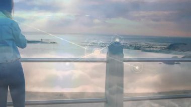 Okyanusun kıyısında, dijital ağ animasyonu olan bir kadın sahne hazırlıyor. Teknoloji, yenilik, okyanus önü, sanal, geleceksel, hologram