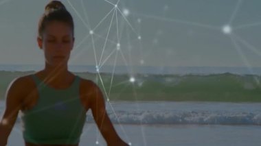 Yoga pratisyeni plajda meditasyon yapıyor ve ağ bağlantıları ile animasyon örtüşüyor. Meditasyon, teknoloji, sağlık, maneviyat, sükunet, denge.