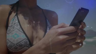 Dijital ağ kaplamalı akıllı telefon kullanan mayo giymiş bir kadın. Teknoloji, bağlantı, plaj, tatil, boş zaman, iletişim