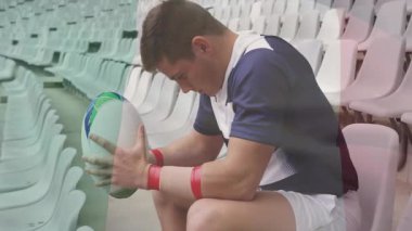 Stadyumda, rugby oyuncusu topu tutuyor ve oturuyor, düşünceli görünüyor. Sporcu, spor, yarışma, açık hava, takım sporu, üniforma