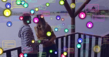 Göl kenarı güvertesinde renkli sosyal medya ikonlarıyla kucaklaşan bir çift. Romantizm, teknoloji, bağlantı, iletişim, dijital