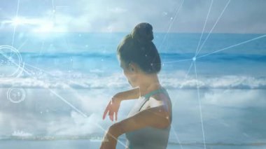 Sahilde yoga pratiği yapan, dijital ağ animasyonu yapan bir kadın. Meditasyon, sağlık, teknoloji, bağlantı, rahatlama, enerji