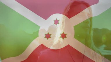 Açık havada duran, Burundi bayrağı arka planda bulanık duran kişi. Vatanseverlik, ulusal gurur, kutlama, birlik, bağımsızlık, kültür