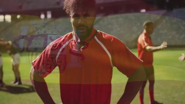 Kırmızı formalı ragbi oyuncusu takım arkadaşlarıyla birlikte sahada güvenle duruyor. Spor, takım çalışması, atlet, yarışma, takım ruhu, açık hava