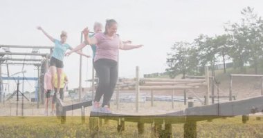 Açık hava kursunda ışınlar üzerinde dengede duran kadınlar, koordinasyon ve takım çalışmasına odaklanıyor. Macera, egzersiz, meydan okuma, denge, fitness, engel