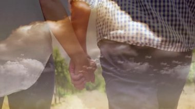 El ele tutuşmalar, bulutlu gökyüzünün altında birlikte yürüyen çift manzarası. Romantik, açık hava, aşk, seyahat, macera, yolculuk