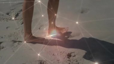 Parlak ağ animasyonu ile kumlu sahilde yürüyen ayaklar. Teknoloji, yenilik, dijital, bağlantı, fütüristik