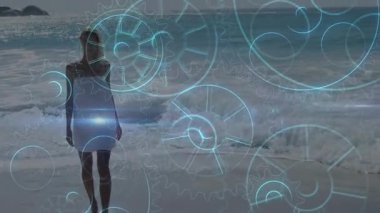 Sahilde yürüyen, arka planda mavi vitesli bir kadın. Teknoloji, yenilik, dijital, fütüristik, kavramsal, soyut