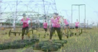 Engelli parkurlarda, pembe tişörtlü kadınlar lastik ve elektrik hatlarıyla uğraşıyorlar. Takım çalışması, meydan okuma, fitness, eğitim, dayanıklılık, güç