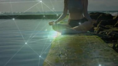 Okyanus tarafından meditasyon yapan, dijital ağ animasyonuyla çevrili, sakin hisseden bir kadın. Meditasyon, sükunet, huzur, farkındalık, rahatlama, sanal