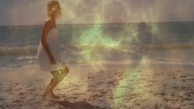 Parlayan ışık efektleriyle dans etmek, plajda beyaz elbiseli bir çocuk. Dans, aydınlanma, yaz, neşe, deniz, kum