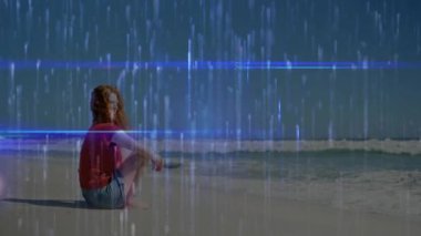 Dijital yağmur ve mavi çizgilerle kaplı sahilde oturan kişi. Gelecekçi, teknoloji, siber uzay, sanal, rahatlama, tatil