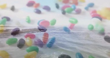 Okyanus dalgaları ve kayalık kıyı şeridi animasyonunun üzerinde renkli jelibonlar yüzüyor. Şeker, şekerleme, şeker, plaj.
