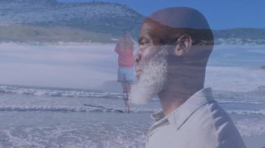 Sahilde duran bir adam okyanusta yürüyen bir kadının animasyonuna bakıyor. Tatil, rahatlama, deniz kıyısı, teknoloji, sanal, erkek