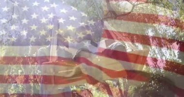 Ormanlık alanda açık hava aktiviteleri yapan insanları çevreleyen Amerikan bayrağının animasyonu. Vatanseverlik, manzara, macera, boş zaman, toplum, açık hava