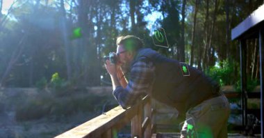 Doğayı fotoğraflamak, ormandaki dijital çevre animasyonlarıyla çevrili bir adam. Teknoloji, artırılmış gerçeklik, fütüristik, yenilik, açık hava