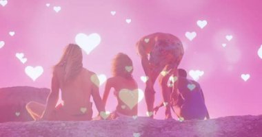 Pembe arka planda kalp animasyonu olan kayaların üzerinde oturan bir grup arkadaş. Arkadaşlık, kaynaşma, açık hava, bağlantı, birlik, boş zaman