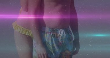 Sahilde, renkli ışık ve parıltılara sahip iki insan animasyon etkisi yaratıyor. Kutlama, plaj partisi, gece hayatı, festival, eğlence, neon