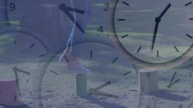 Saatin üzerinde ahşap bir kütük üzerinde dengede duran kişi çimenli alanda animasyona bakıyor. Denge, meydan okuma, zaman yönetimi, açık hava, doğa, konsept