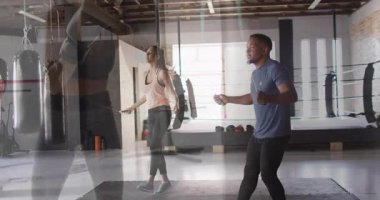 Enerjik bir şekilde ip atlayan, spor salonunda animasyon ve boks ekipmanlarıyla iki kişi. Egzersiz, spor, egzersiz, antrenman, atlama, dayanıklılık.